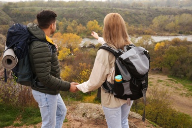 Couple of hikers with travel backpacks enjoying nature on autumn day, back view