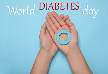 Image of Woman showing blue paper circle as World Diabetes Day symbol on color background, top view
