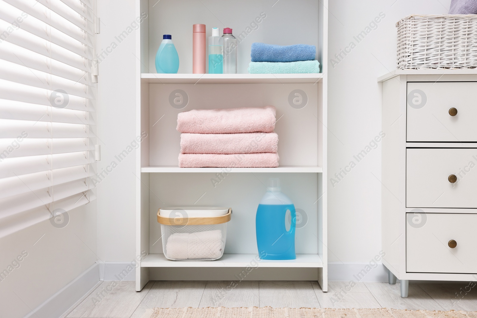 Photo of Shelving unit with stacked clean towels and toiletries in room