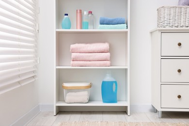 Shelving unit with stacked clean towels and toiletries in room
