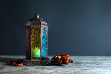 Photo of Muslim lamp, dates and misbaha on wooden table. Fanous as Ramadan symbol
