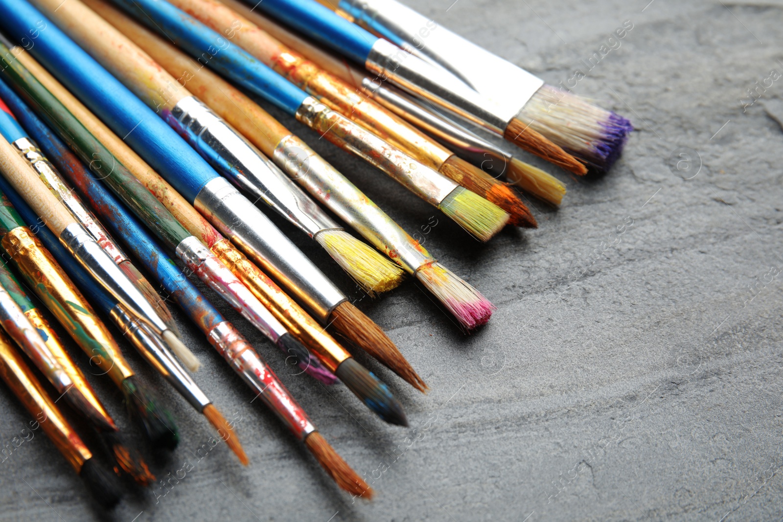 Photo of Different paint brushes on grey table, closeup