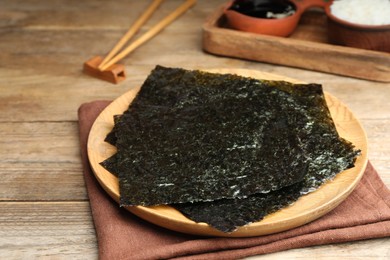 Plate with dry nori sheets on wooden table