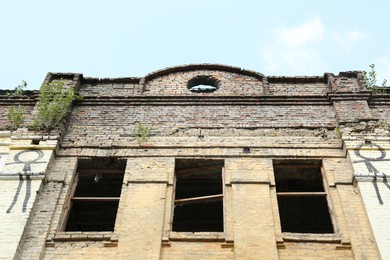 Photo of Abandoned building with broken windows against blue sky, low angle view