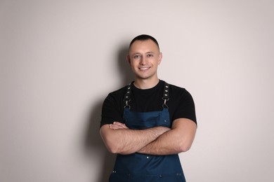 Photo of Portrait of happy young waiter in uniform on light background
