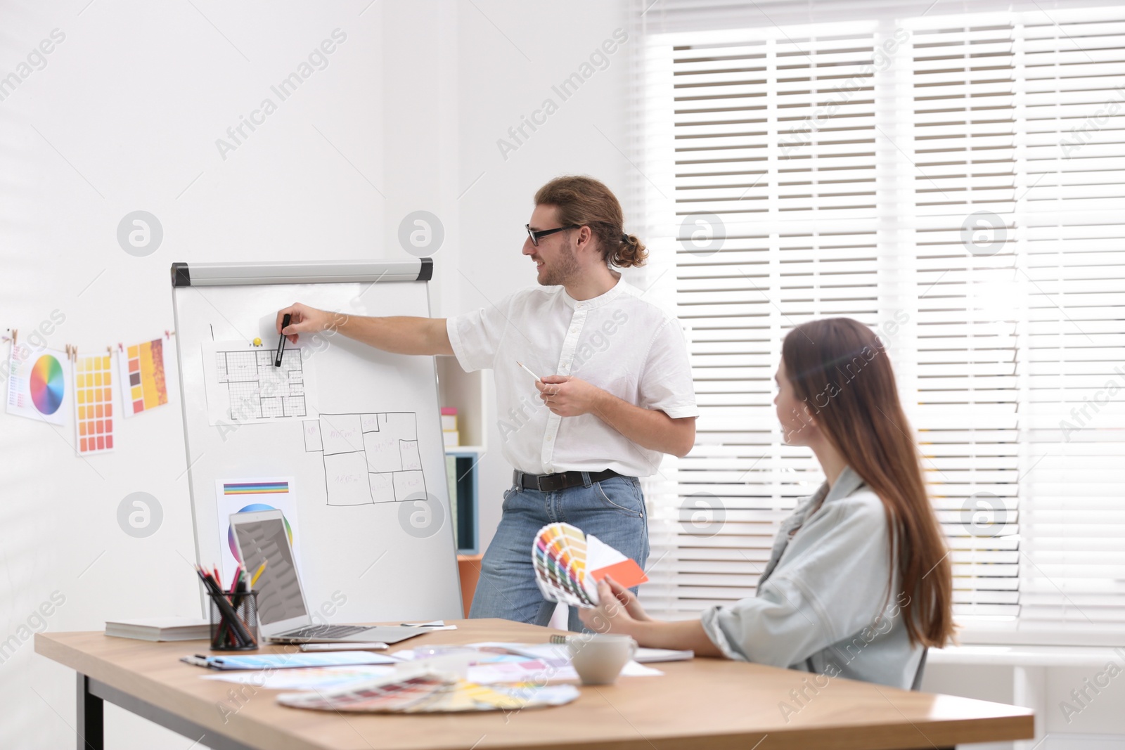 Photo of Professional interior designer near whiteboard and colleague in office