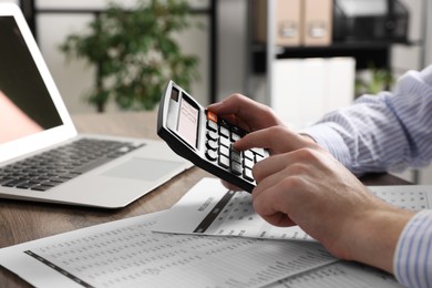 Photo of Man using calculator at table in office, closeup