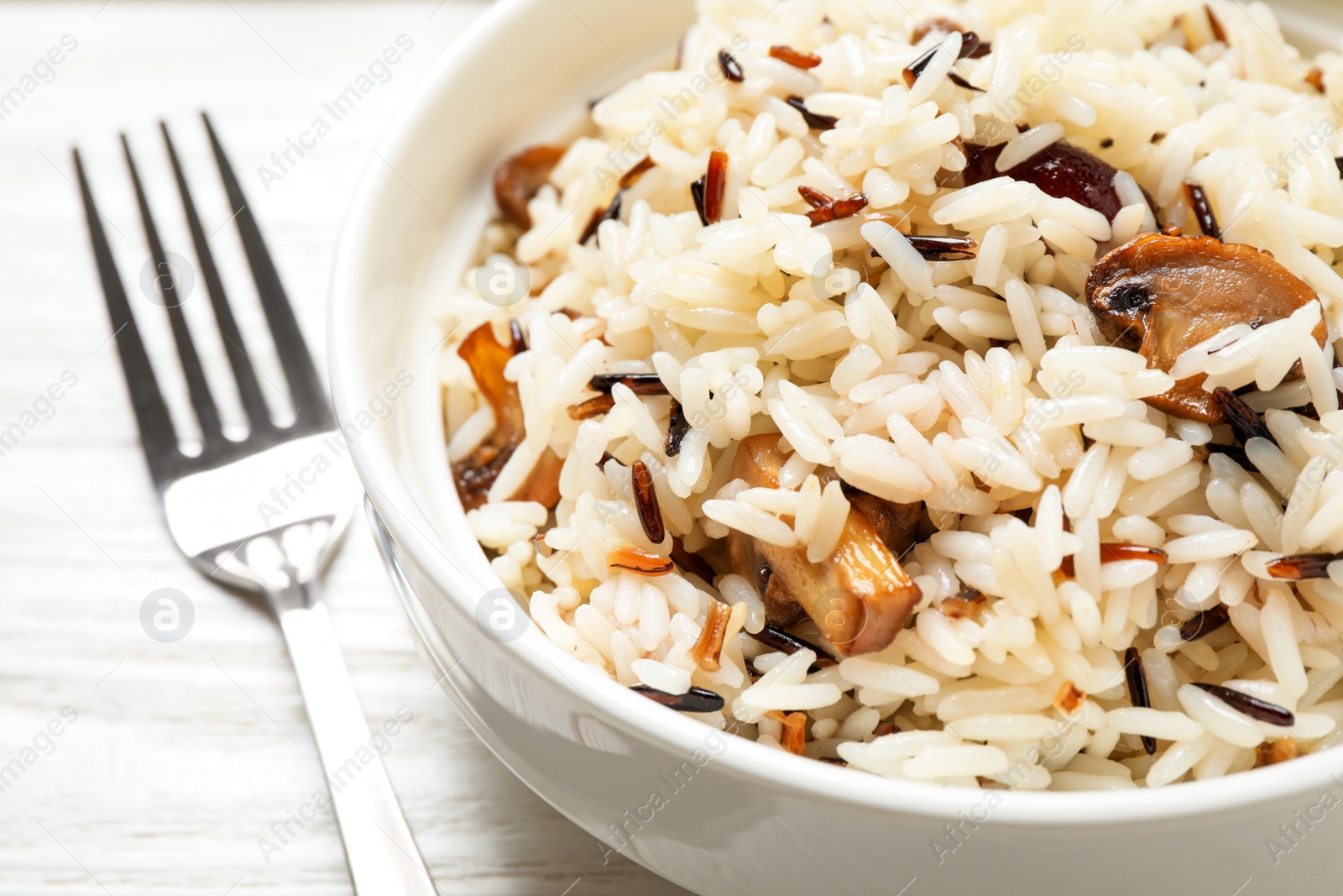 Photo of Delicious rice pilaf with mushrooms on white table, closeup