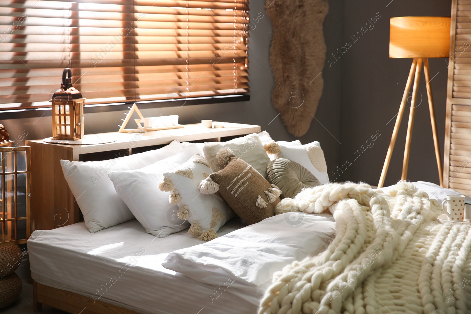 Photo of Cozy bedroom interior with knitted blanket and cushions