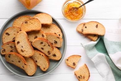 Photo of Sweet hard chuck crackers with raisins and jam on white wooden table, flat lay