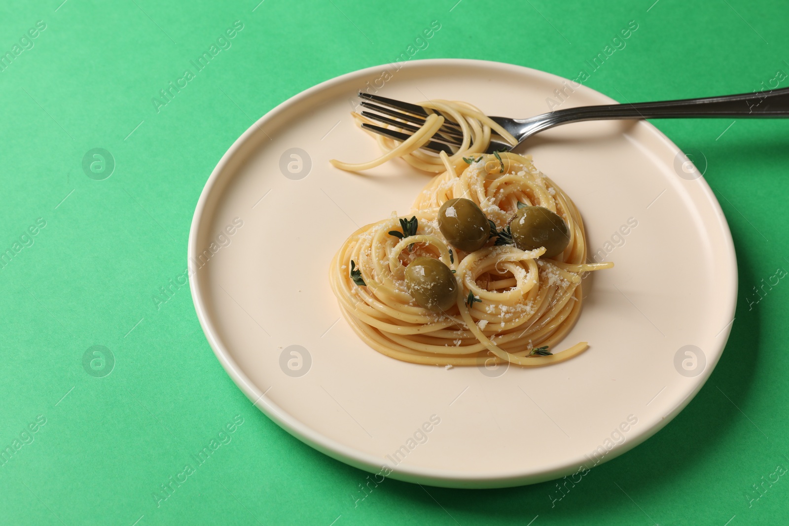 Photo of Heart made of tasty spaghetti, fork, olives and cheese on green background