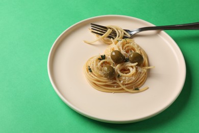 Photo of Heart made of tasty spaghetti, fork, olives and cheese on green background