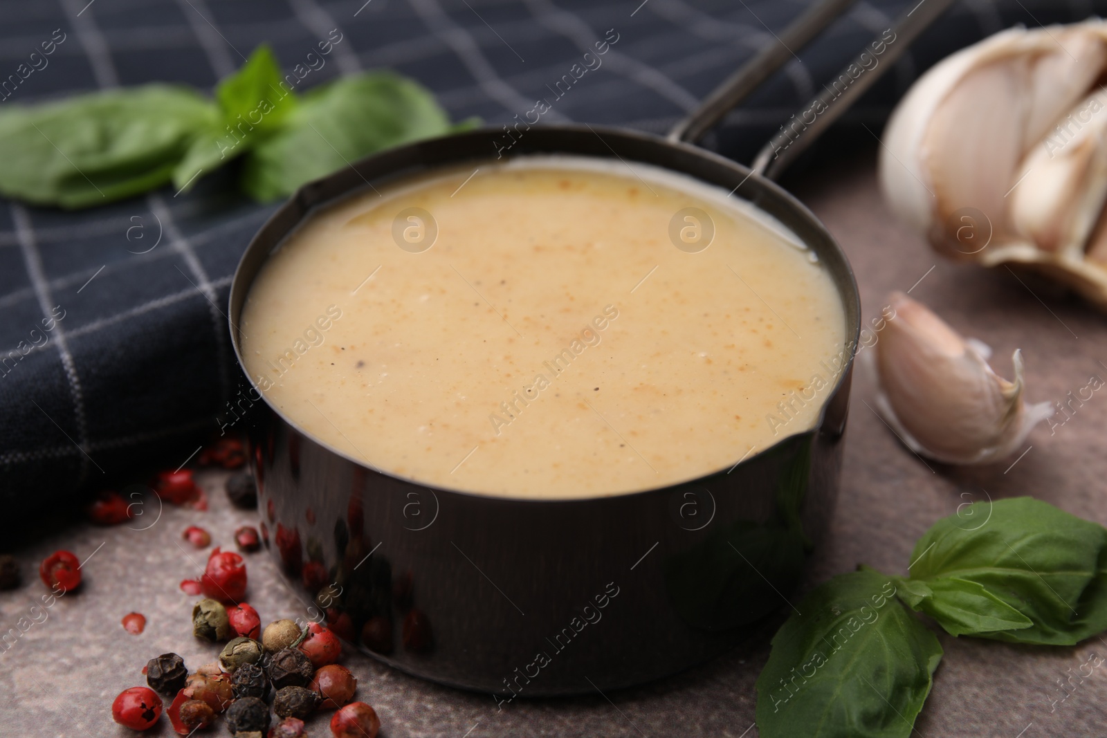 Photo of Delicious turkey gravy, basil, peppercorns and garlic on brown textured table, closeup