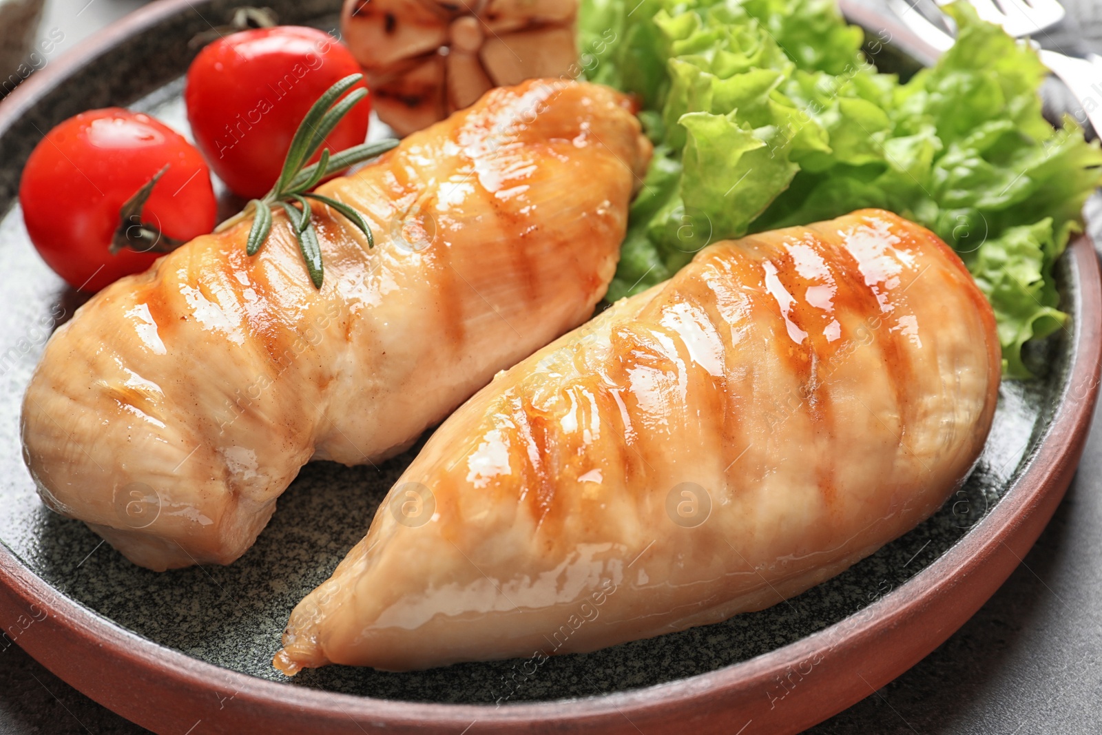 Photo of Plate with grilled chicken breasts and garnish on table, closeup