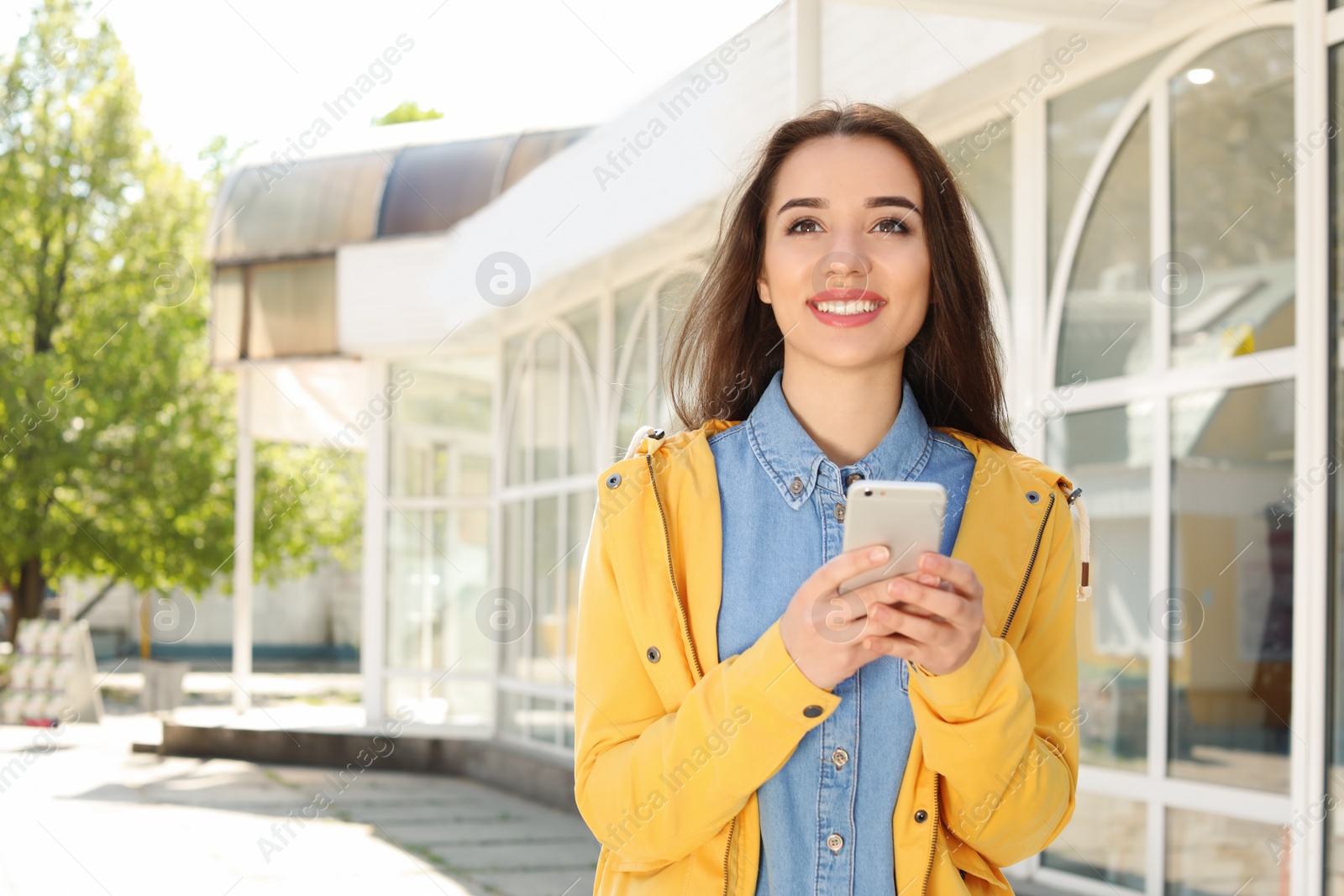 Photo of Young woman using phone outdoors on sunny day