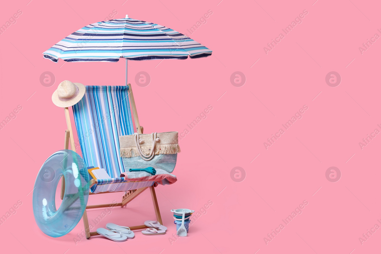 Photo of Deck chair, umbrella and other beach accessories on pink background, space for text. Summer vacation