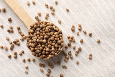 Photo of Spoon with dried coriander seeds on light cloth, top view