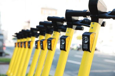 Photo of Many modern electric scooters on city street, closeup. Rental service