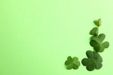 Photo of Clover leaves on green background, flat lay with space for text. St. Patrick's Day symbol