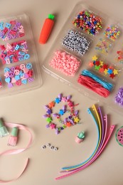 Photo of Handmade jewelry kit for kids. Colorful beads, wristbands, ribbon and bracelets on beige background, flat lay