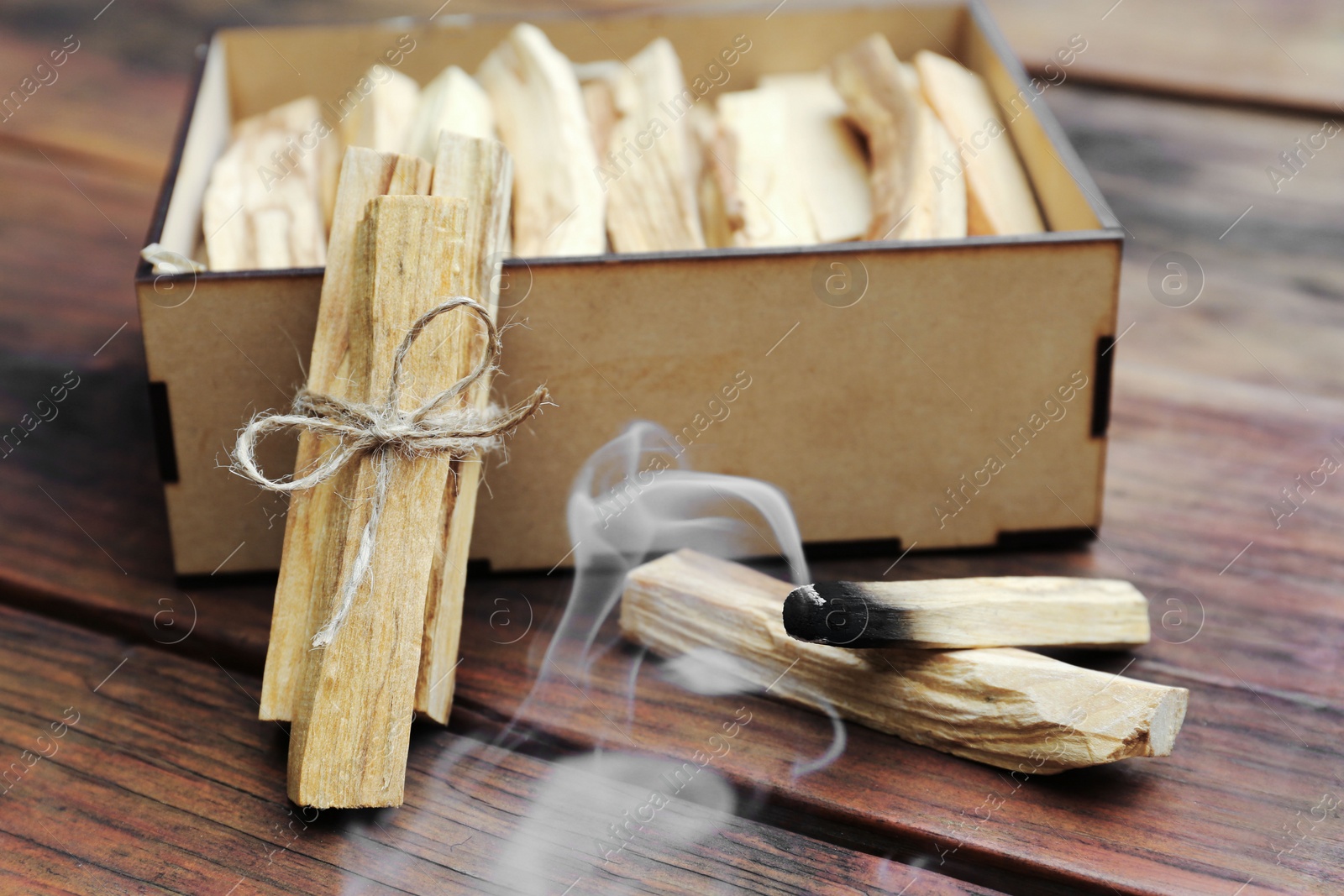 Photo of Many Palo Santo sticks and one smoldering on wooden table