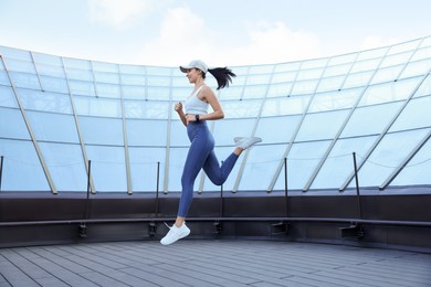 Beautiful woman in stylish sportswear jumping outdoors