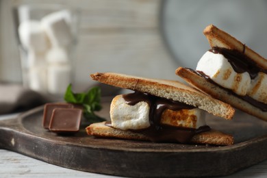 Photo of Delicious marshmallow sandwiches with chocolate on white wooden table, closeup