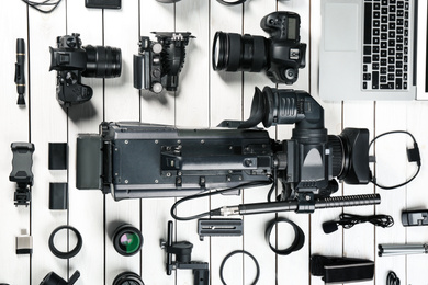 Flat lay composition with video camera and other equipment on white wooden table