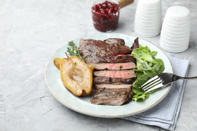 Photo of Delicious roasted beef meat, caramelized pear and greens served on light textured table