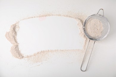 Frame made of flour and sieve on white table, top view. Space for text