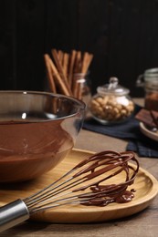Bowl and whisk with chocolate cream on wooden table