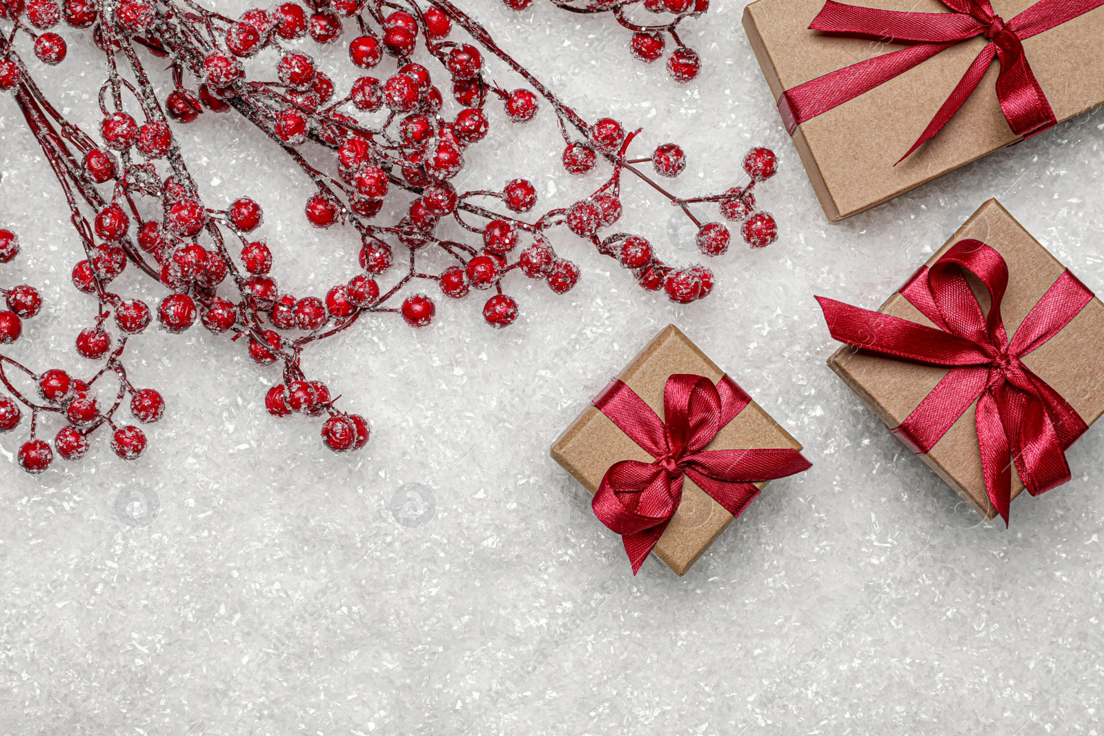 Photo of Gift boxes and decorative branches on artificial snow, flat lay with space for text. Christmas celebration