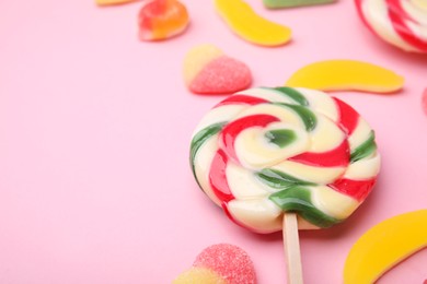 Photo of Many different jelly candies and lollipop on pink background, closeup. Space for text