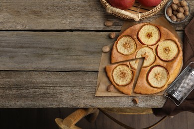 Tasty apple pie, nutmeg seeds and fresh fruits on wooden table, flat lay. Space for text