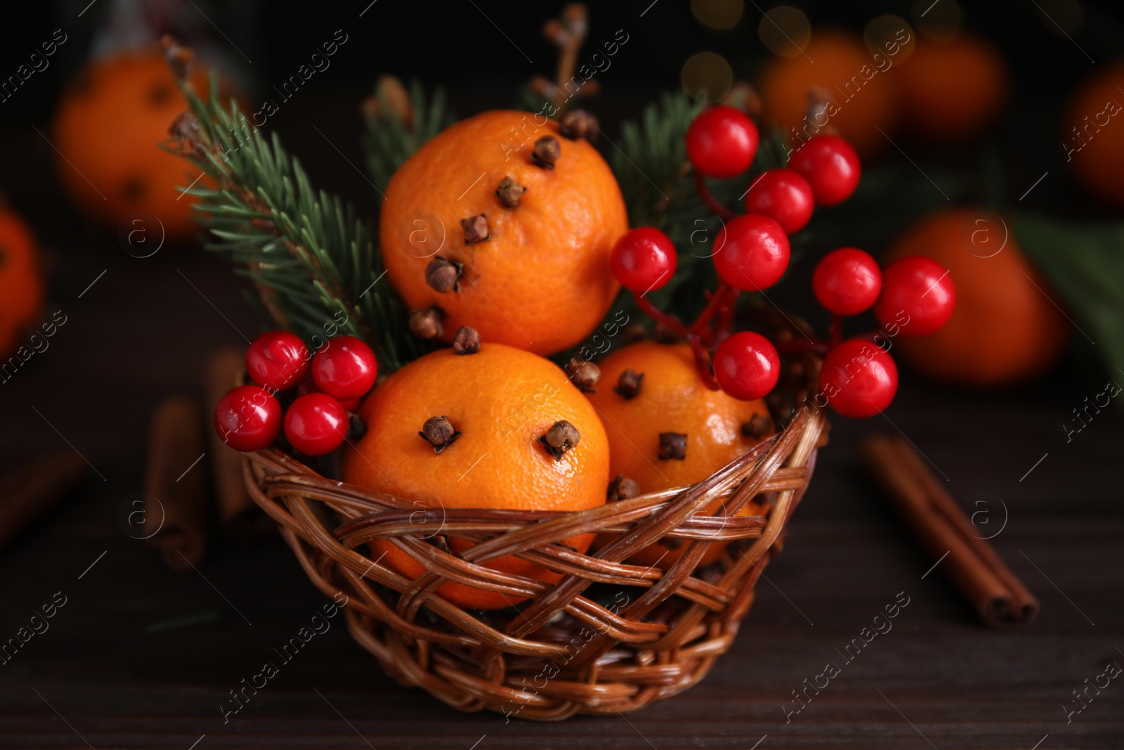 Photo of Christmas composition with tangerine pomander balls in wicker bowl on wooden table