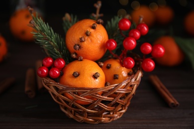 Photo of Christmas composition with tangerine pomander balls in wicker bowl on wooden table