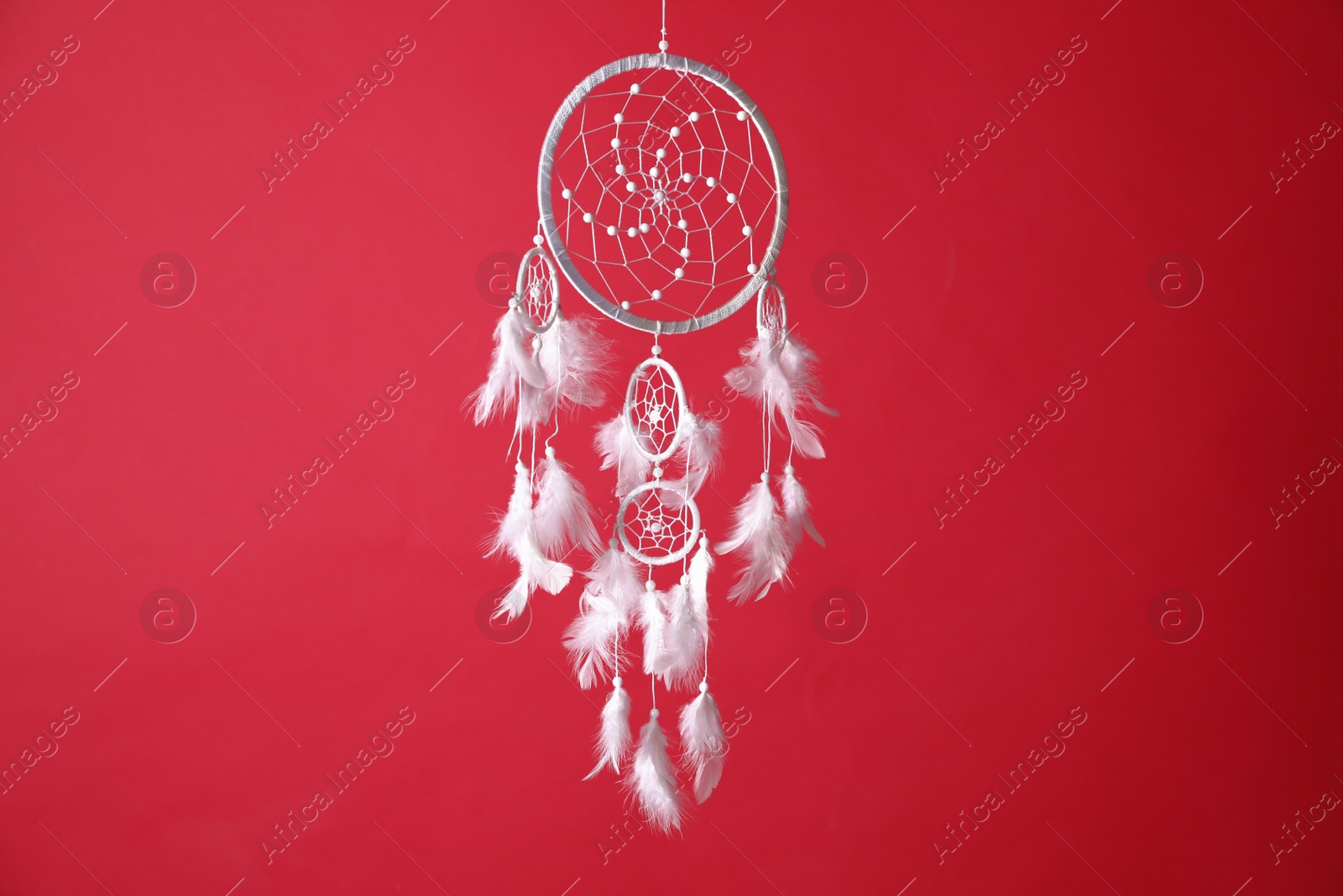 Photo of Beautiful dream catcher hanging on red background