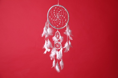 Photo of Beautiful dream catcher hanging on red background