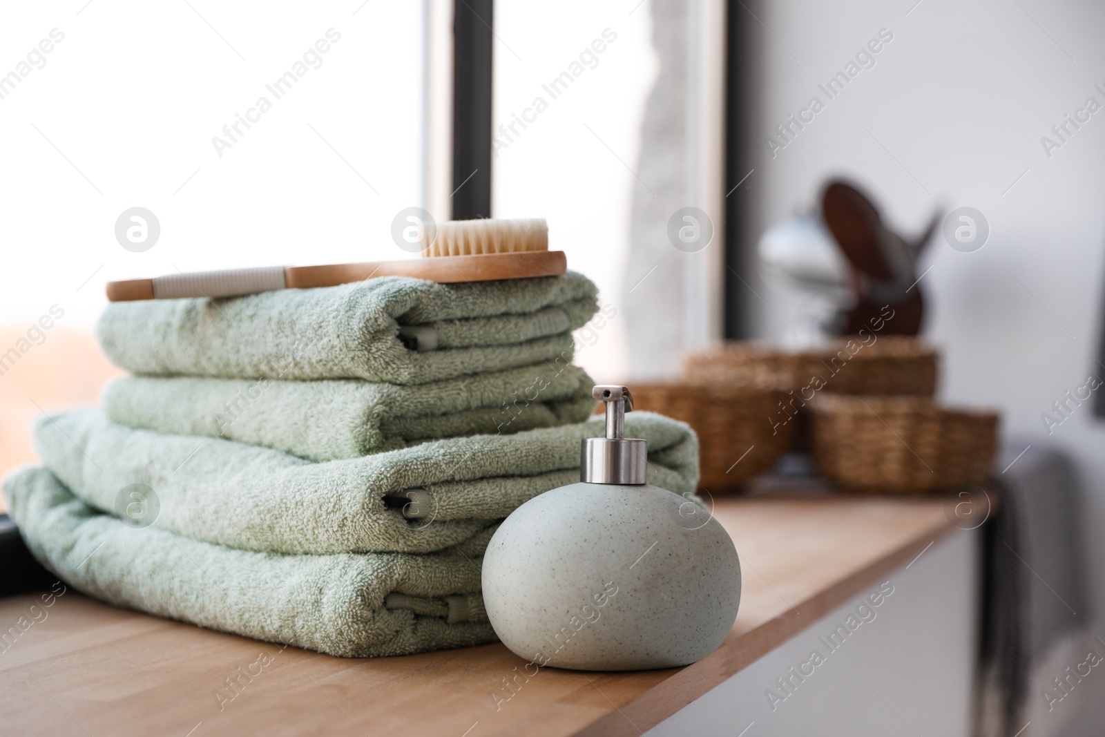 Photo of Towels, soap dispenser and shower brush on windowsill in bathroom