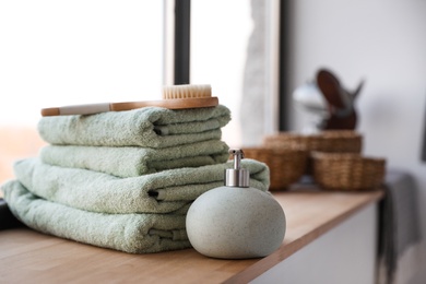 Towels, soap dispenser and shower brush on windowsill in bathroom