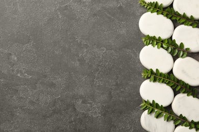 Photo of Spa stones and branches of plant on grey table, flat lay. Space for text