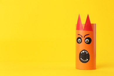 Photo of Funny orange monster on yellow background, space for text. Halloween decoration