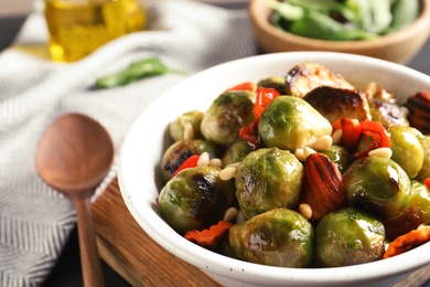Photo of Bowl of warm salad with Brussels sprouts and carrots on table