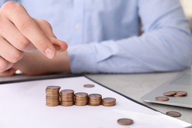 Photo of Man stacking coins at table indoors, closeup