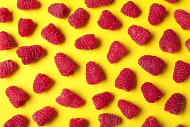 Flat lay composition with delicious ripe raspberries on yellow background