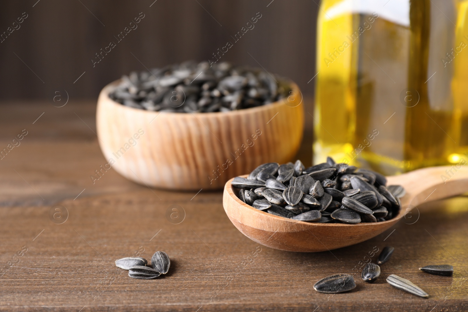 Photo of Sunflower seeds and oil on wooden table. Space for text