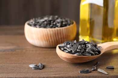 Sunflower seeds and oil on wooden table. Space for text