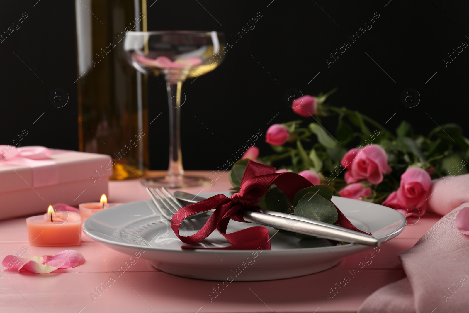 Photo of Place setting with roses and candles on pink wooden table, closeup. Romantic dinner