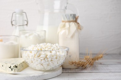 Different fresh dairy products and wheat ears on white wooden table. Space for text