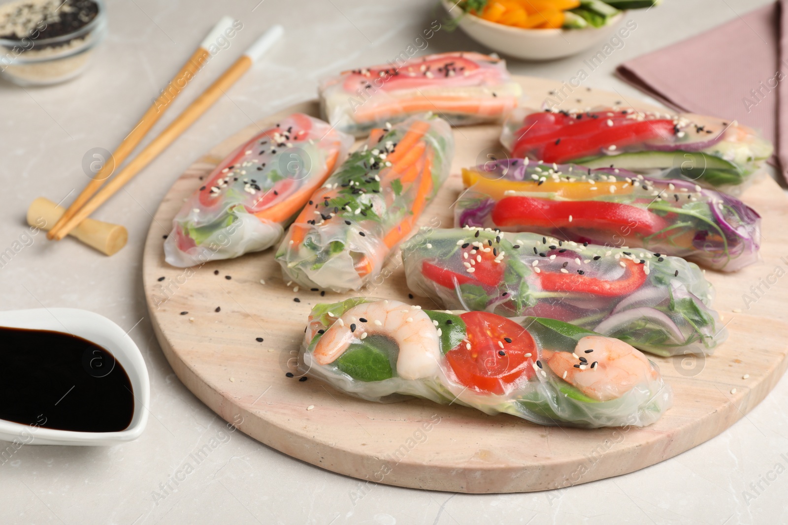 Photo of Delicious rolls wrapped in rice paper served on light table, closeup